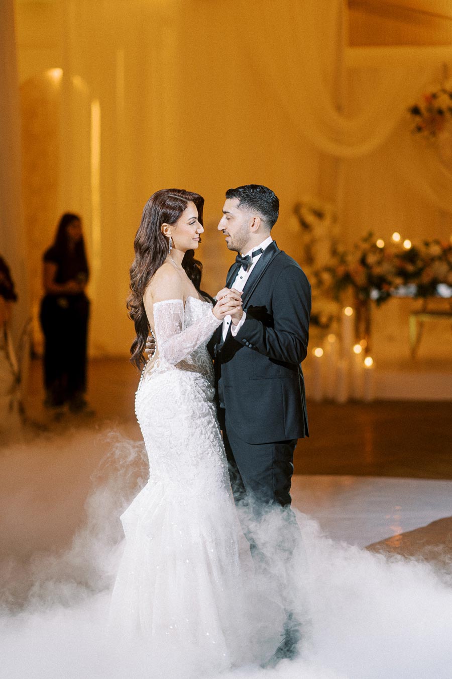 A bride and groom sharing their first dance at a wedding reception, surrounded by soft lighting and elegant decor.