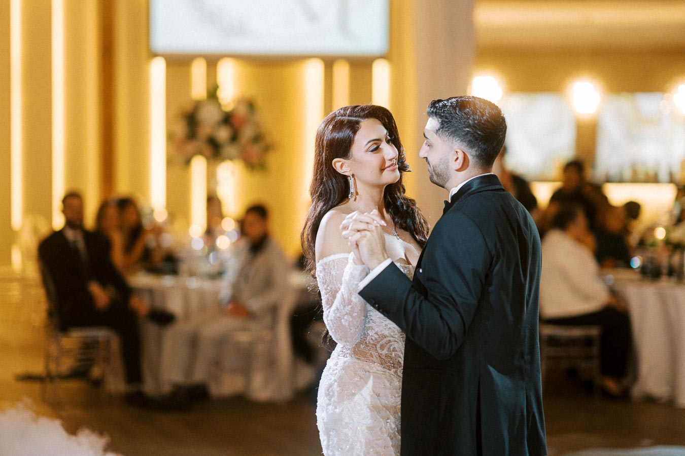 Elegant bride and groom sharing a romantic first dance at their wedding reception, surrounded by guests in a beautifully