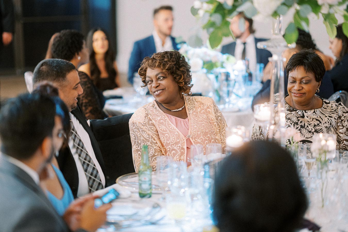 A group of elegantly dressed people enjoying a formal event at a beautifully decorated table adorned with flowers and
