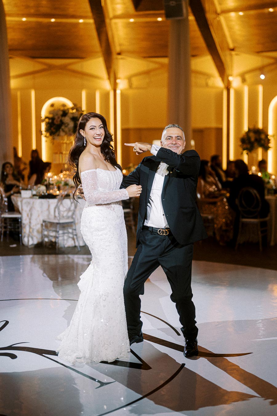 Elegant wedding couple dancing joyfully in a beautifully decorated ballroom reception area.