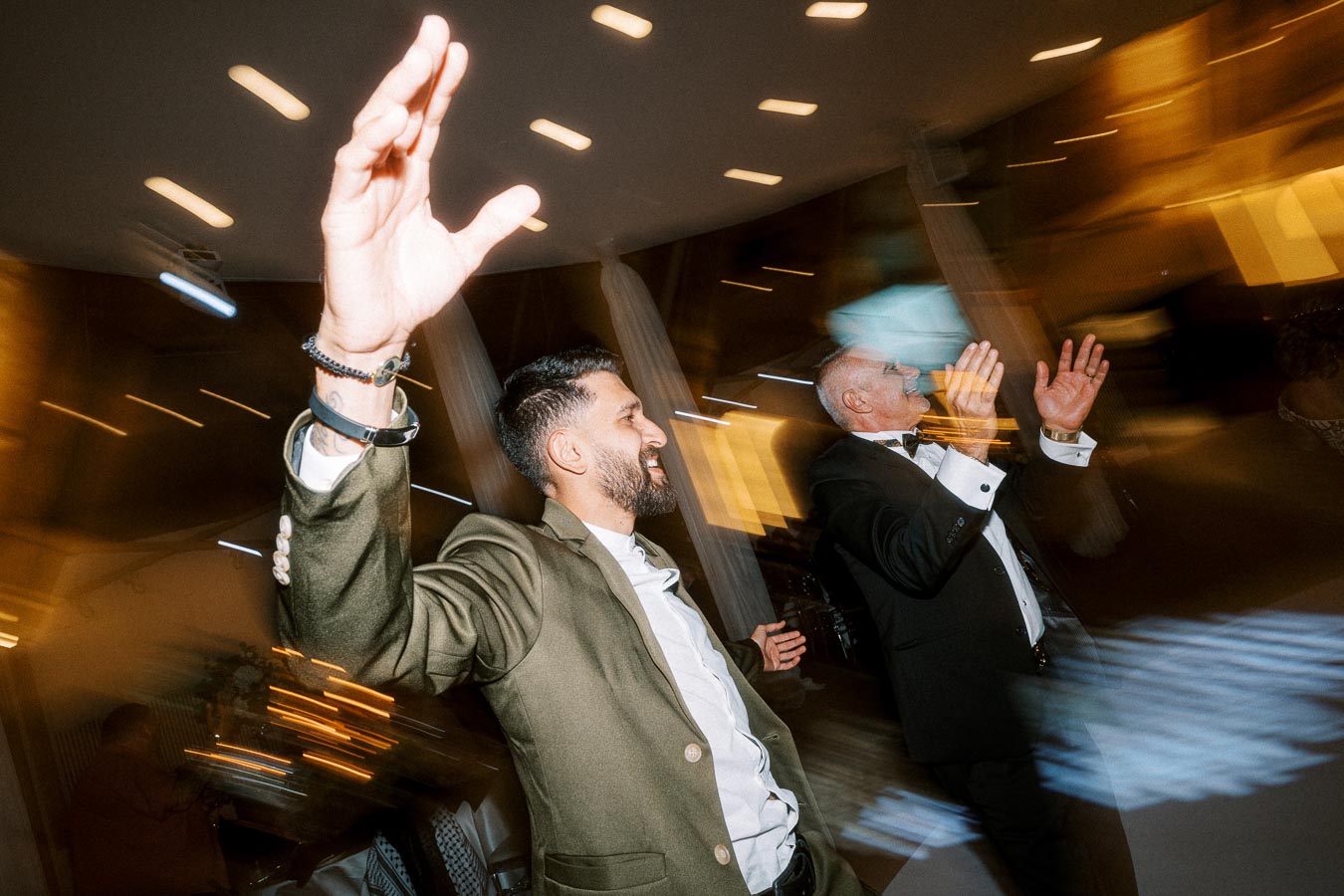 Two men joyfully dancing at a lively indoor event, with bright lights