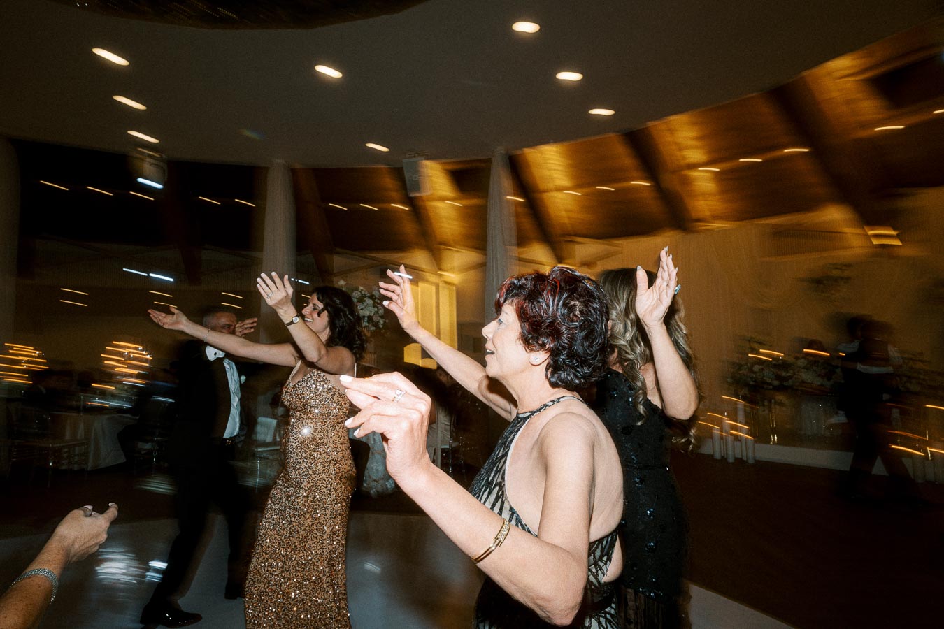 Group of people dancing energetically at a lively indoor party with elegant decor and soft lighting.