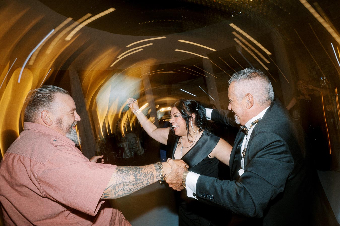 Three people joyfully dancing at a lively party with dynamic motion blur in the background, capturing the festive atmosphere.