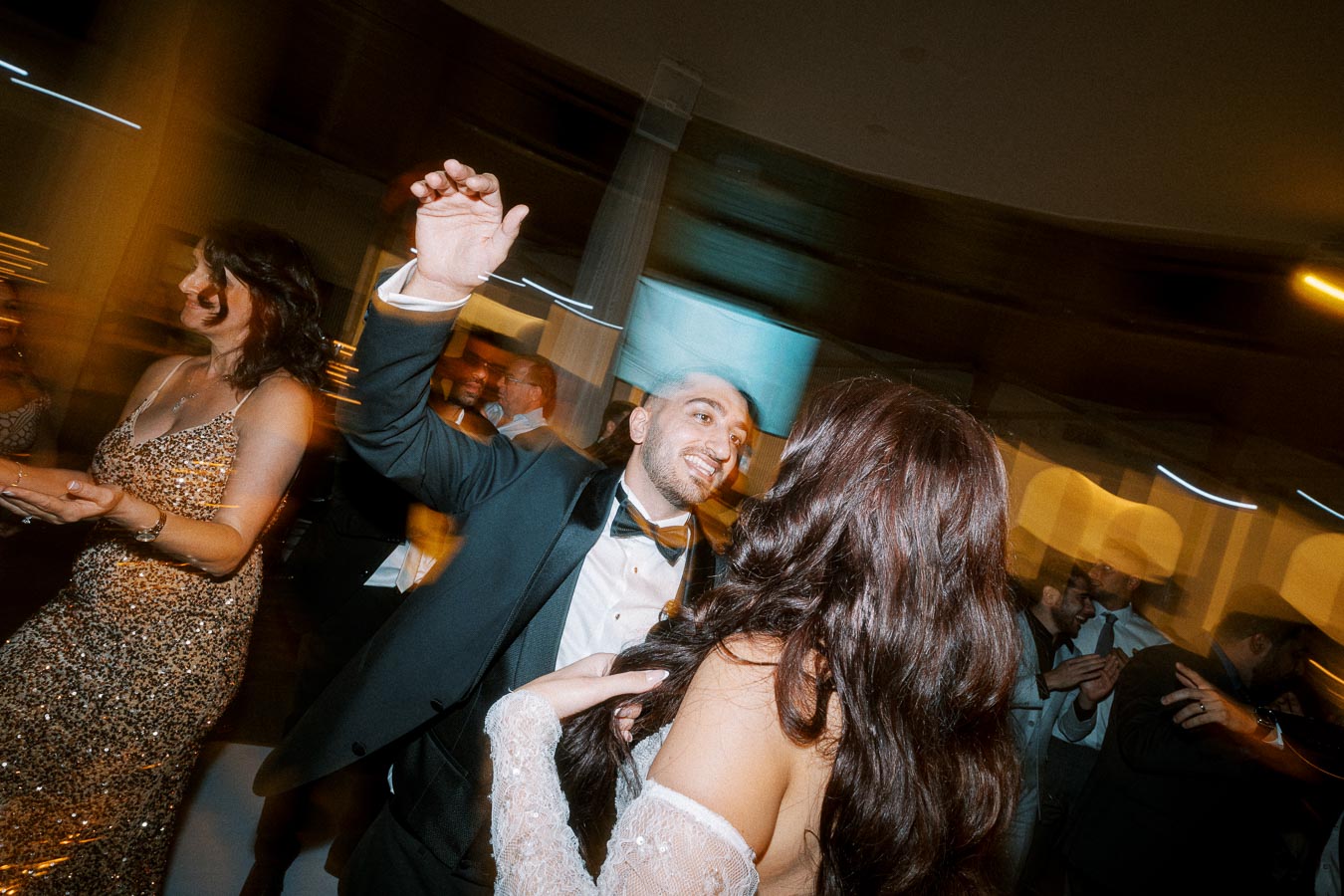 A vibrant wedding celebration with guests dancing energetically on the dance floor, dressed in elegant evening attire.