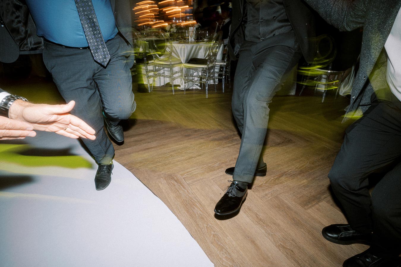 Guests dancing energetically at a wedding reception, with motion blur capturing the lively atmosphere on the wooden dance