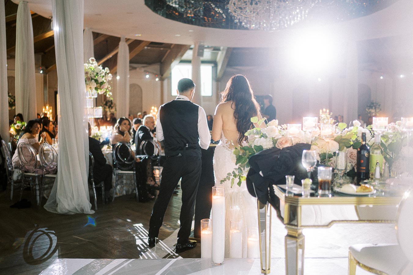 A bride and groom giving a speech at their wedding reception in a beautifully decorated venue with candles and floral