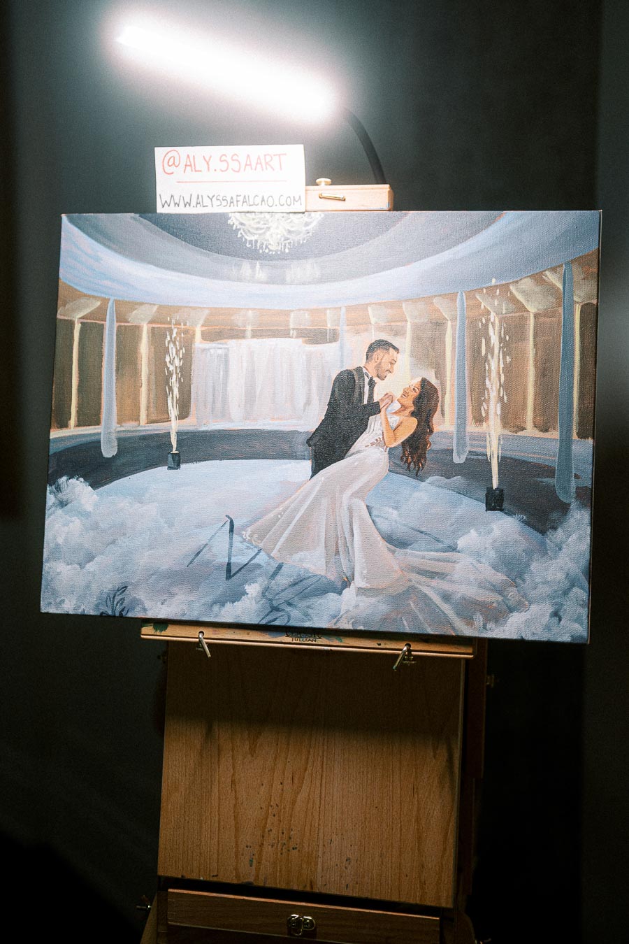 Painting of a couple dancing in an elegant setting with chandeliers and pillars, displayed on an easel.