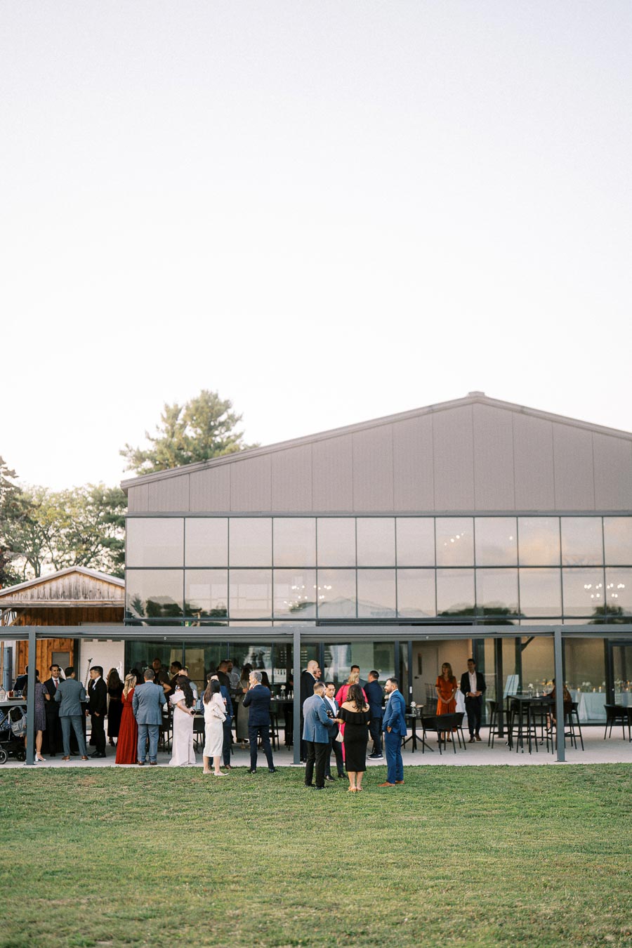 Guests mingling at an outdoor event in front of a modern glass building.