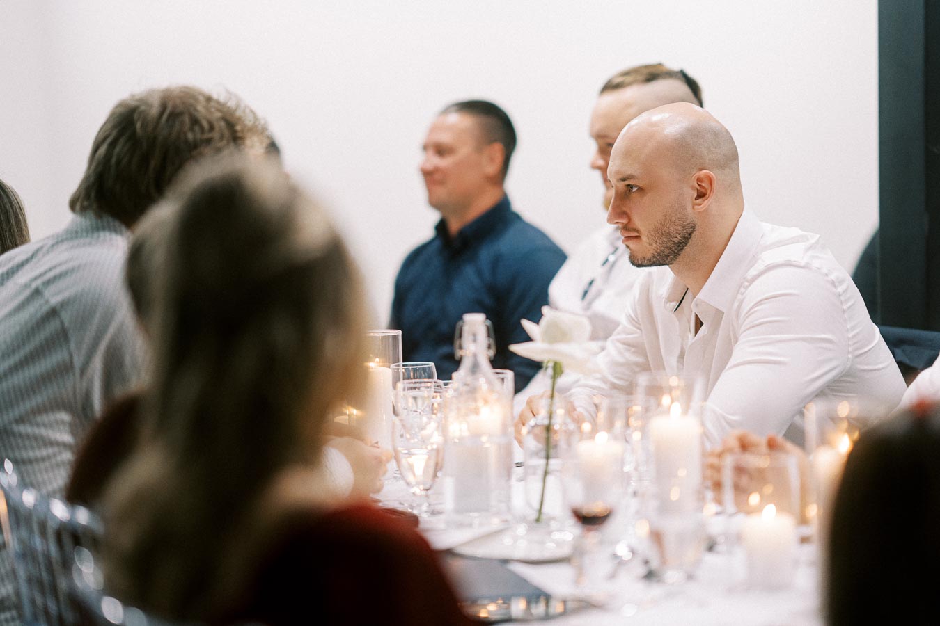 People sitting at an elegantly decorated dinner table during a formal event, with soft candlelight creating a warm ambiance.