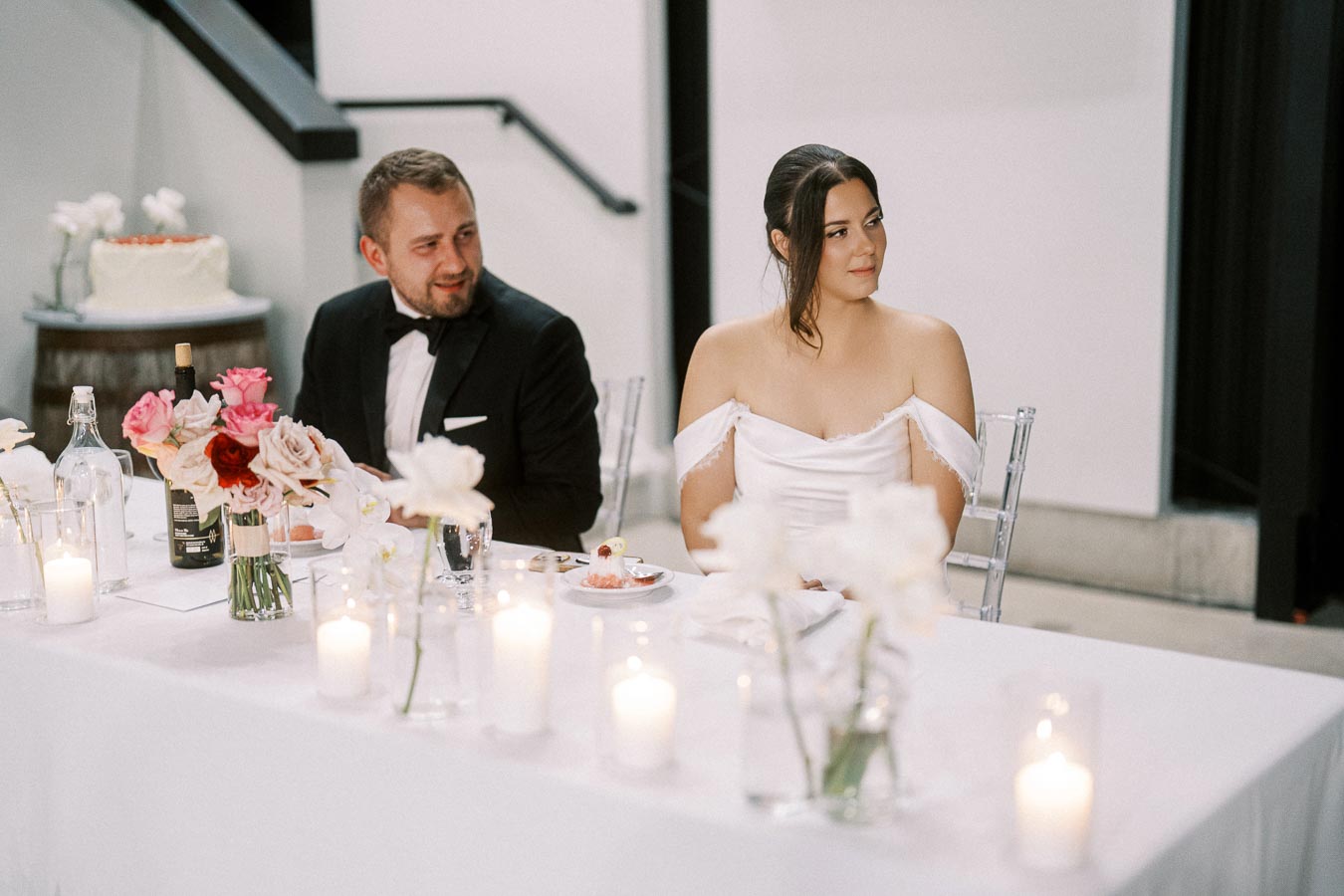 A bride and groom sitting at a beautifully decorated table with candles and flower arrangements during their wedding reception.