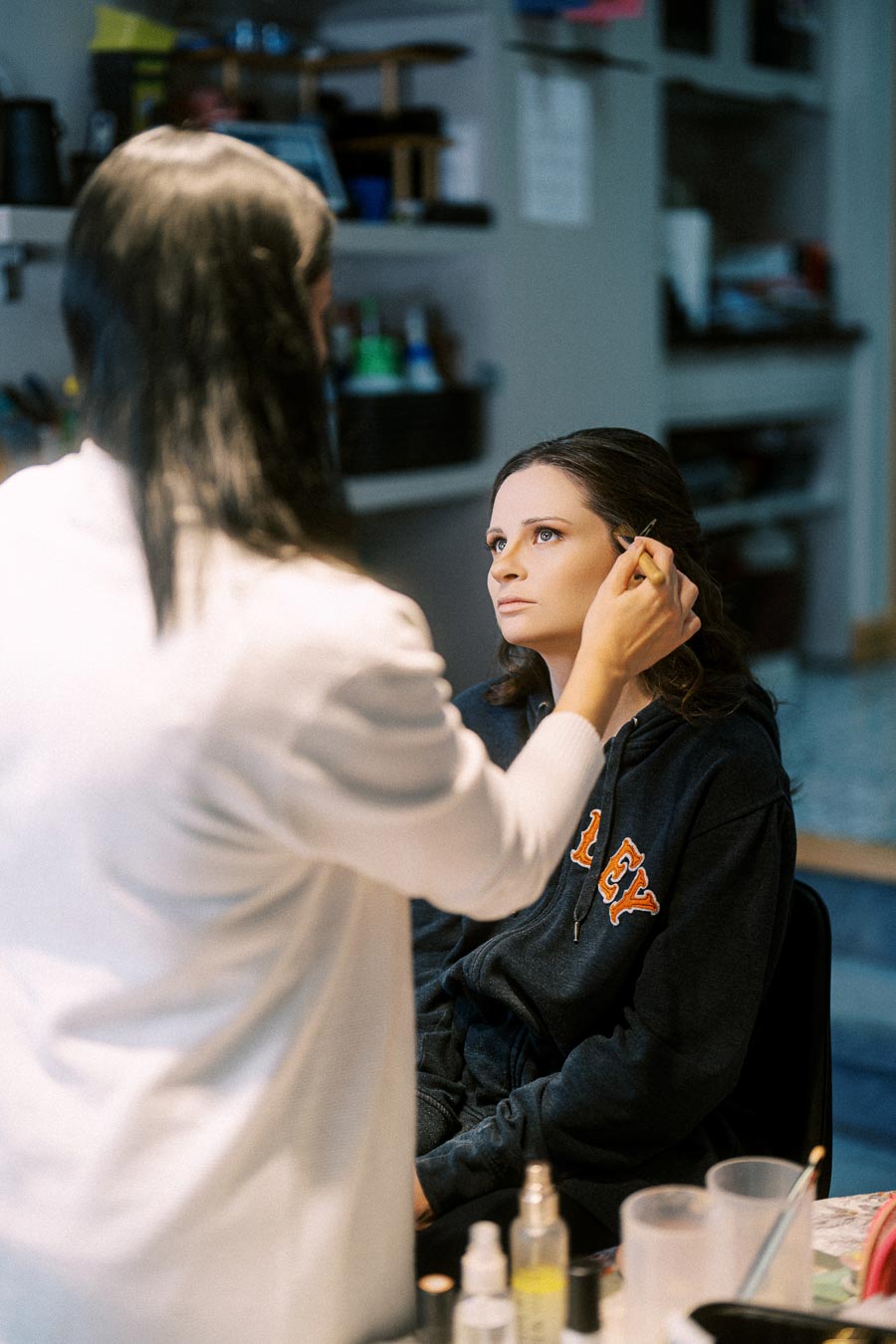 A makeup artist applying cosmetics to a woman's face in a well-lit beauty salon, highlighting preparation and styling for an
