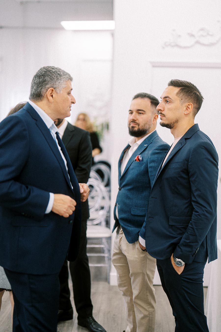 Three men in business attire engaged in conversation at a formal event, highlighting professional networking and corporate