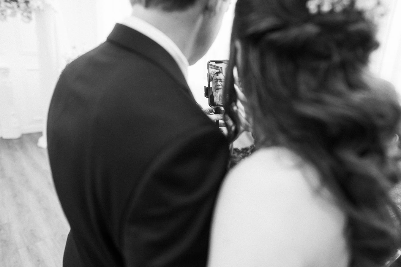 Black and white photo of a couple taking a selfie with a phone, capturing a special moment together.