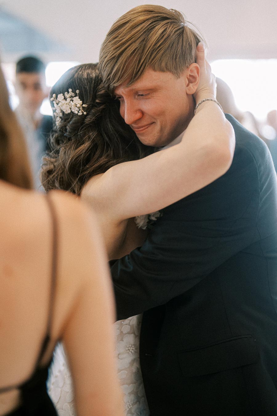 Emotional embrace between a smiling couple at a wedding reception, showcasing love and connection.