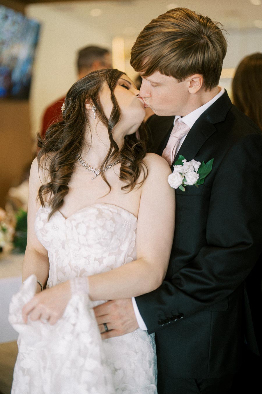 Romantic wedding couple sharing a kiss on their special day; bride in a beautiful white lace gown and groom in a classic