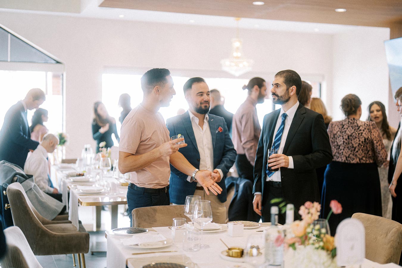 A group of professionally dressed individuals engaged in conversation at a formal event or business gathering, set in a