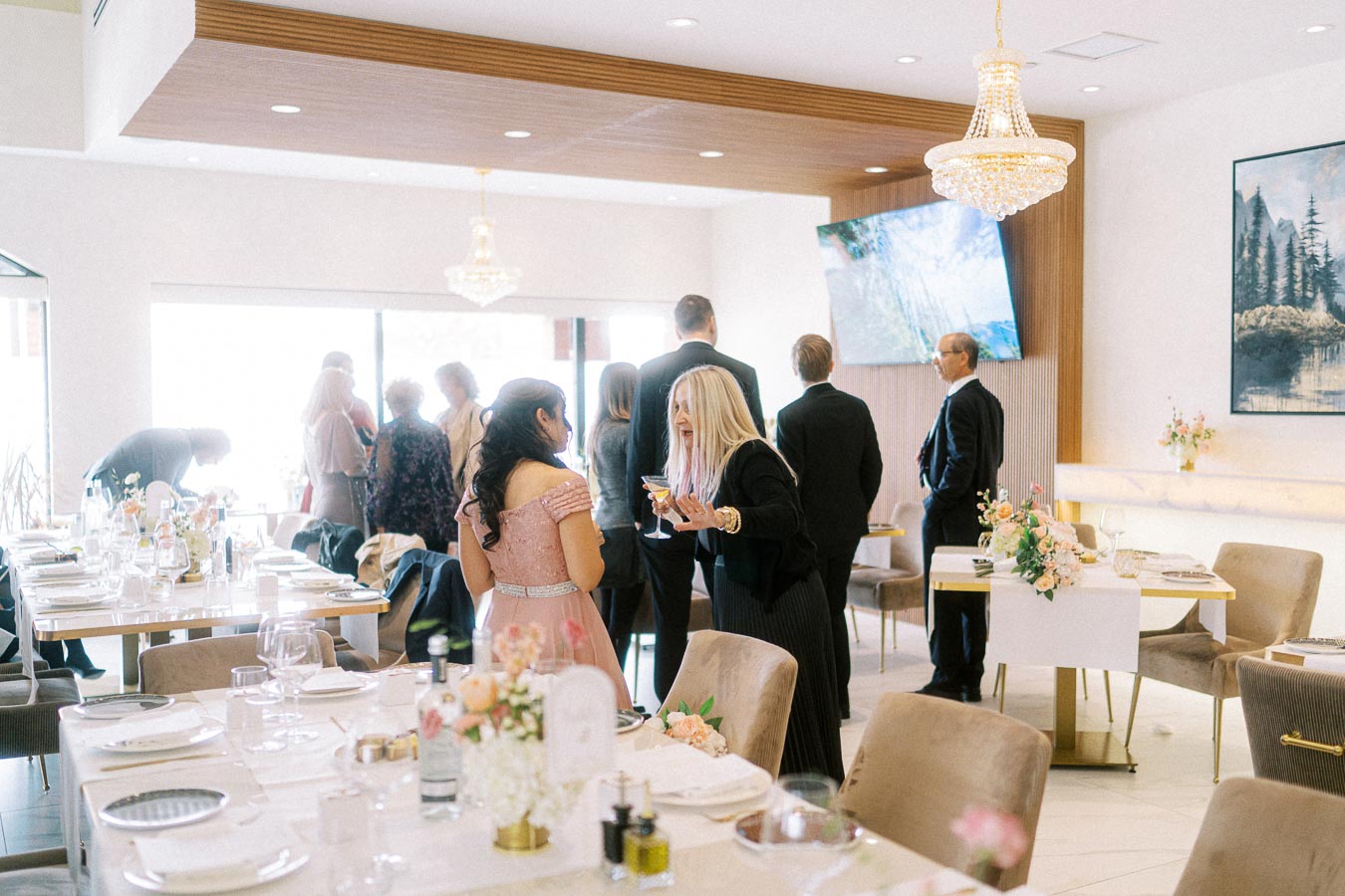 Elegant brunch gathering in a bright, modern venue, featuring guests in formal attire engaged in conversation around