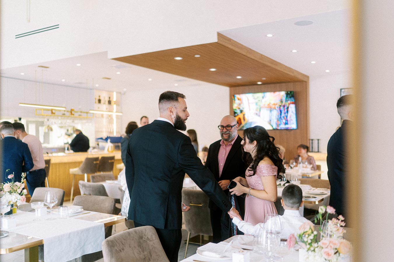 Elegant gathering in a stylish restaurant with people in formal attire socializing, surrounded by beautifully set tables and