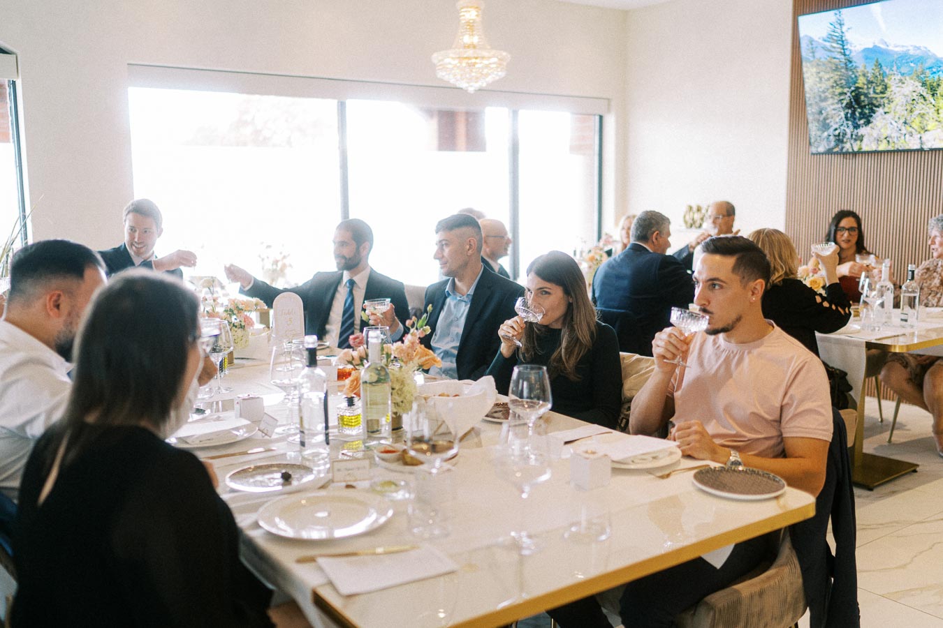 Group of people enjoying a formal gathering at a banquet table, featuring elegantly arranged table settings and floral