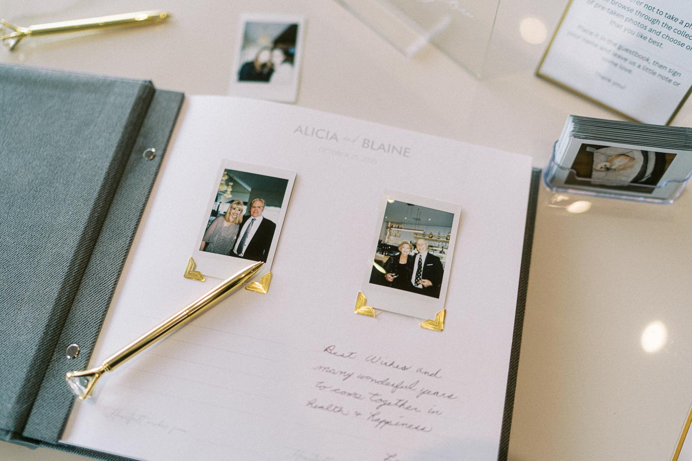 Open guestbook at a wedding reception featuring Polaroid photos and handwritten messages for the couple, placed on a white
