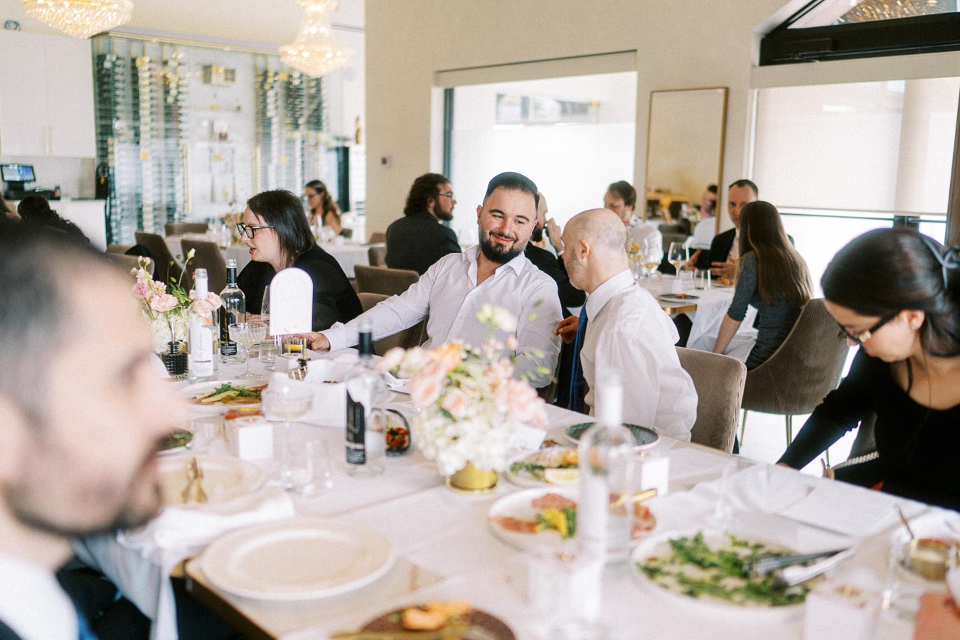 A group of people enjoying a formal gathering at a restaurant, sitting around a beautifully set table with elegant tableware