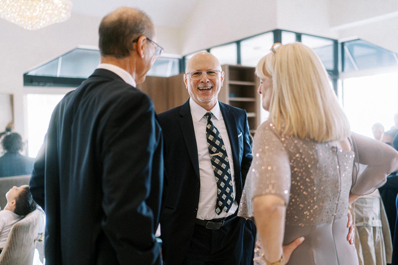 A group of formally dressed individuals engaging in a lively conversation at a social event, set in a modern and elegant