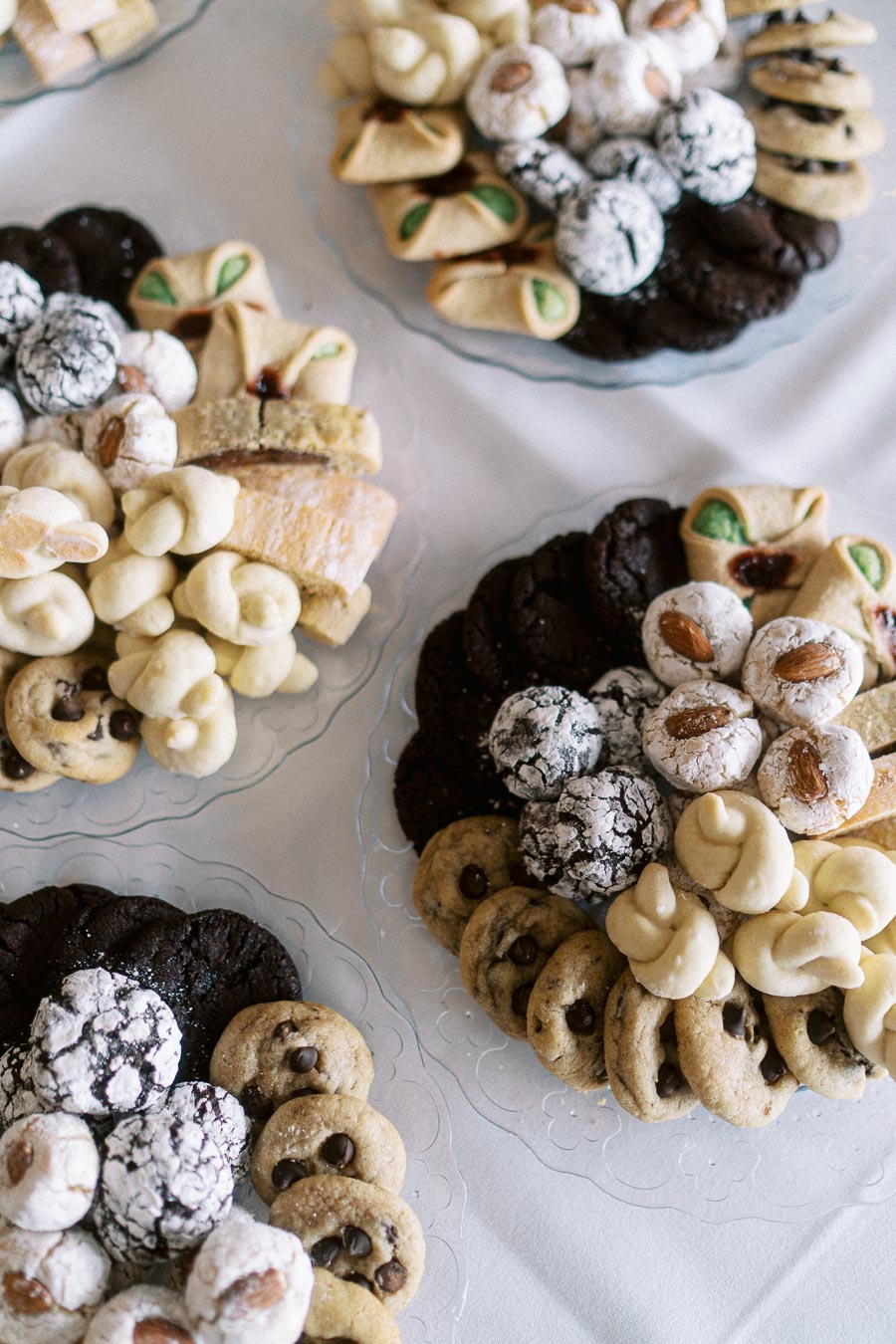 Assorted Italian cookies displayed on glass platters, featuring a variety of textures, shapes, and flavors, including