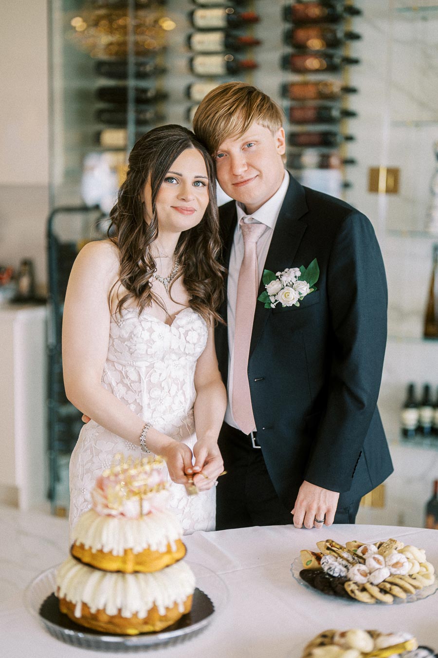 Newlywed couple cutting wedding cake, adorned with floral decorations, during their elegant reception in a sophisticated