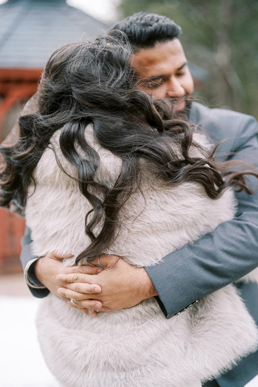 Couple embracing warmly outdoors, wearing winter attire and in a heartfelt hug, capturing a moment of affection and closeness.