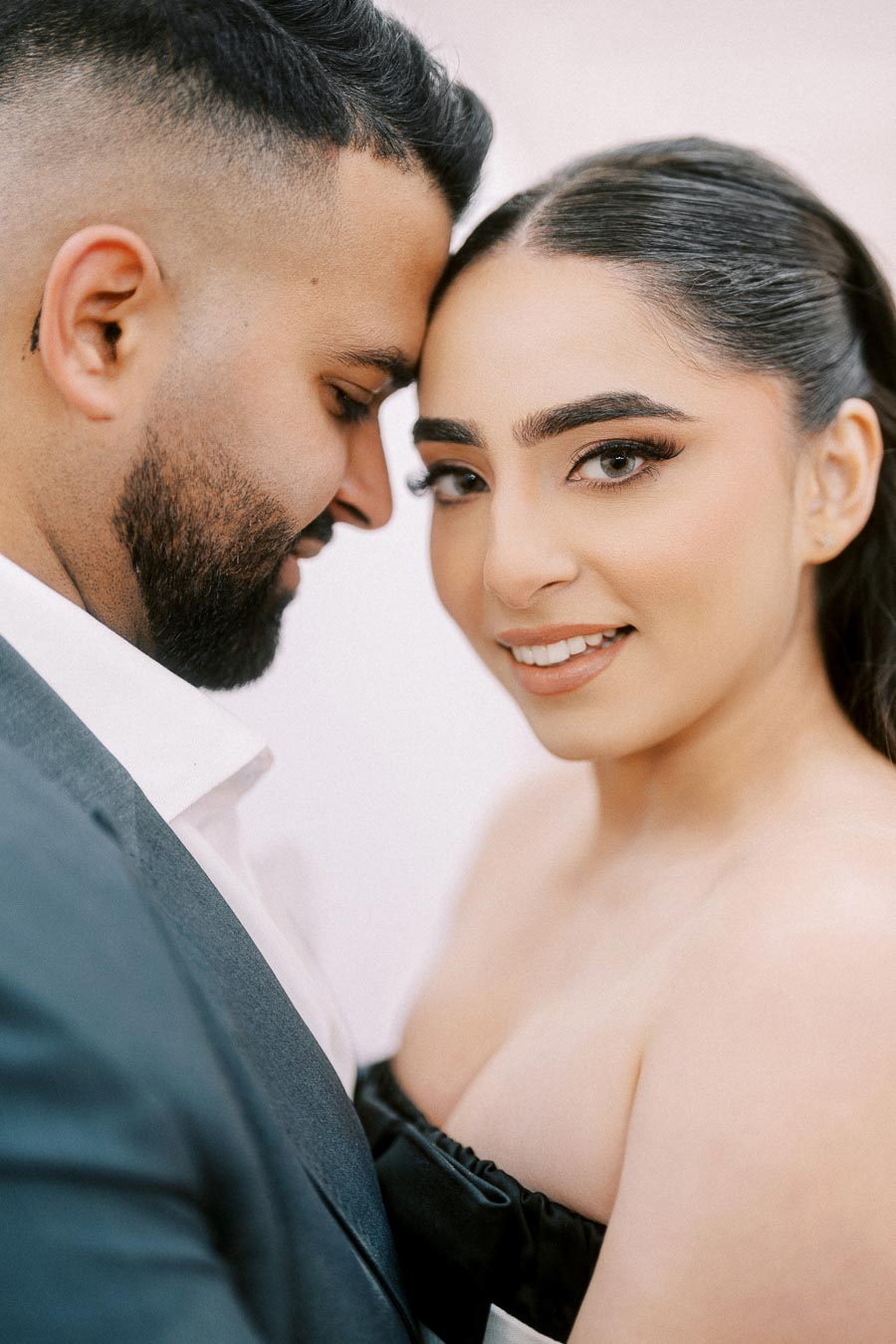 Close-up of a smiling couple embracing, focusing on their happy expressions and loving connection, dressed elegantly for a special occasion.