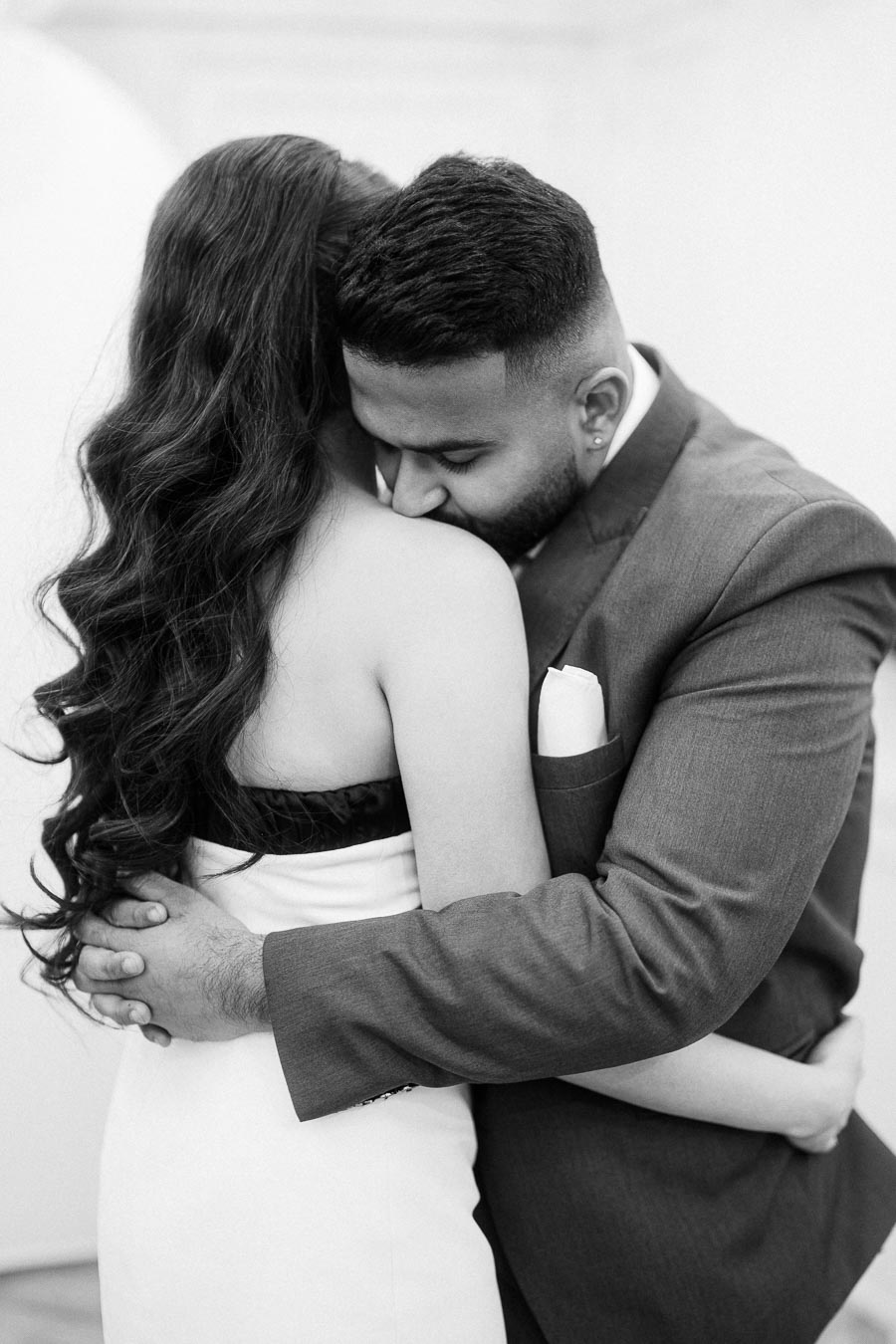 A black and white photo of a couple embracing, with the man gently hugging the woman, capturing an intimate and loving moment.