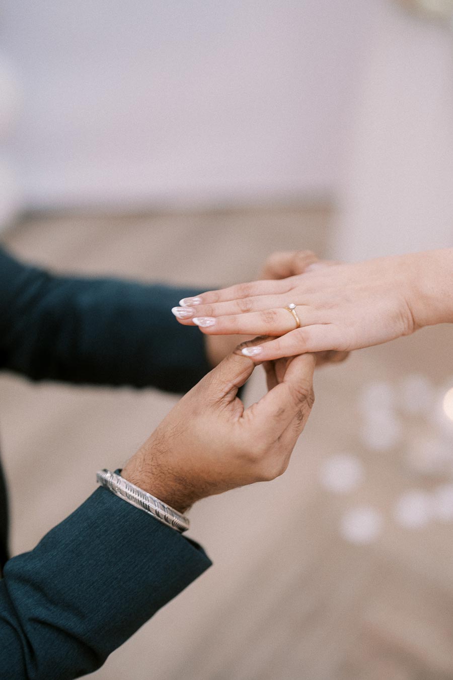 A close-up of a person placing a gold engagement ring with a small diamond on another person's finger, symbolizing a romantic proposal.