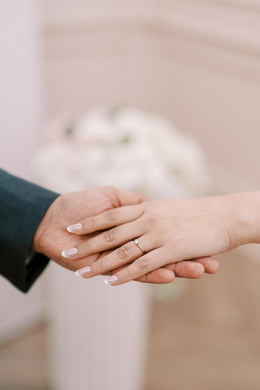 Close-up of couple's hands with an engagement ring on the woman's hand, symbolizing love and commitment at a wedding ceremony.