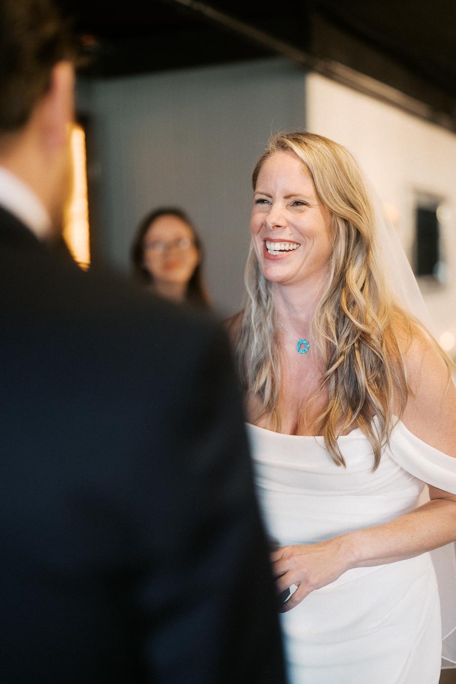 Smiling bride in white dress during wedding ceremony indoors.