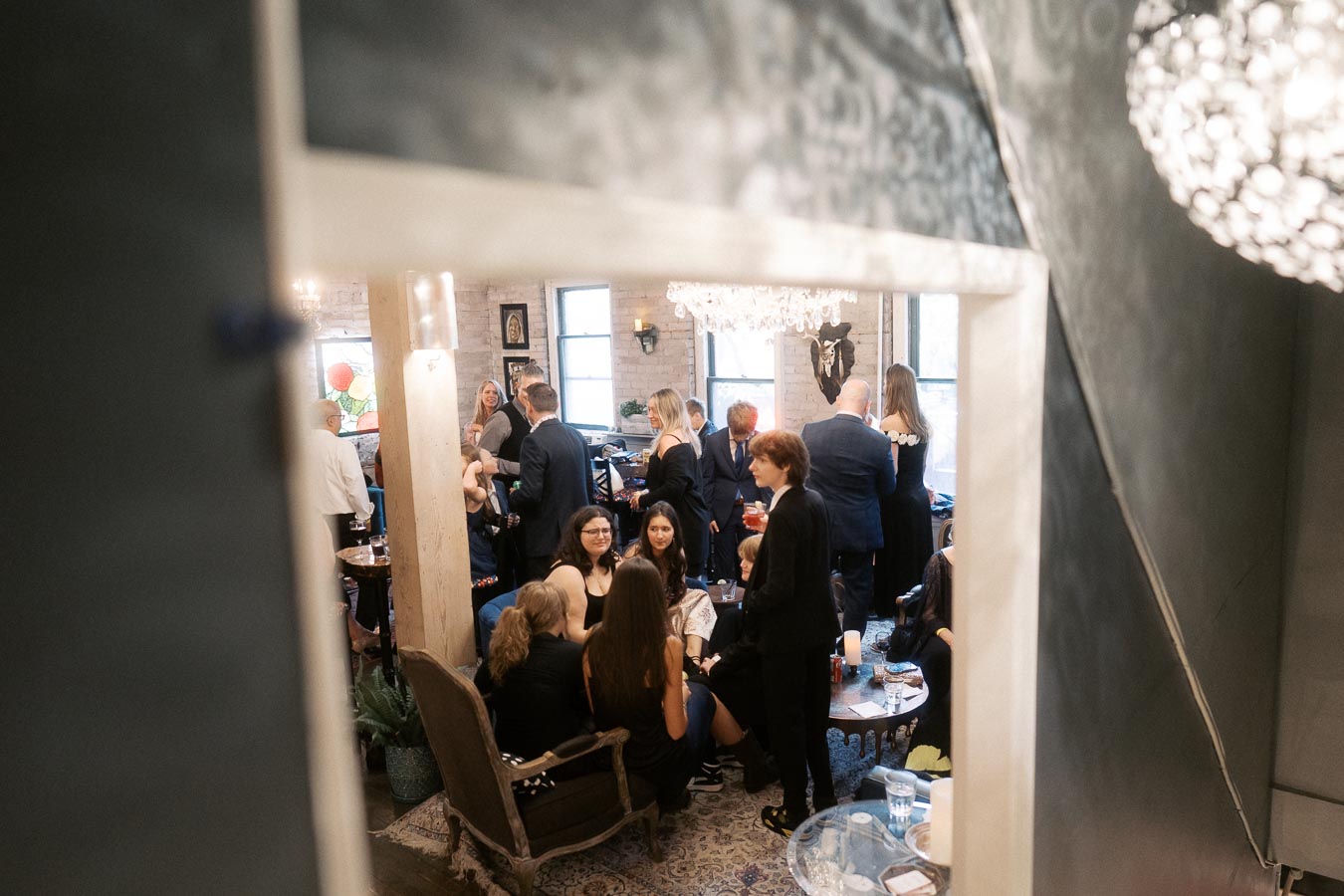 A lively social gathering in a stylish indoor setting, featuring people engaging in conversations and enjoying a sophisticated ambiance with elegant decor and warm lighting.