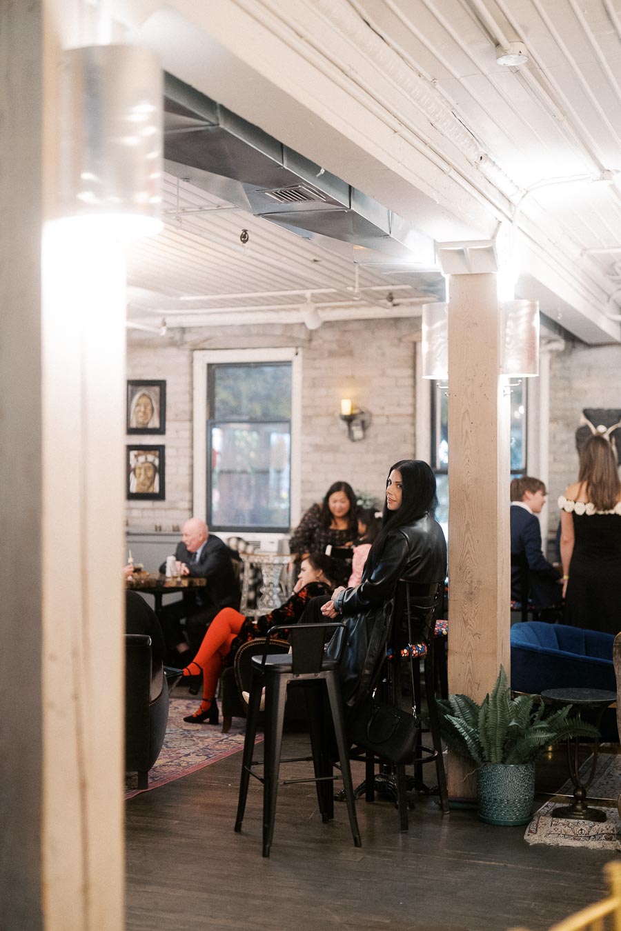 Cozy indoor cafe setting with people socializing, featuring modern decor, exposed brick walls, and ambient lighting.