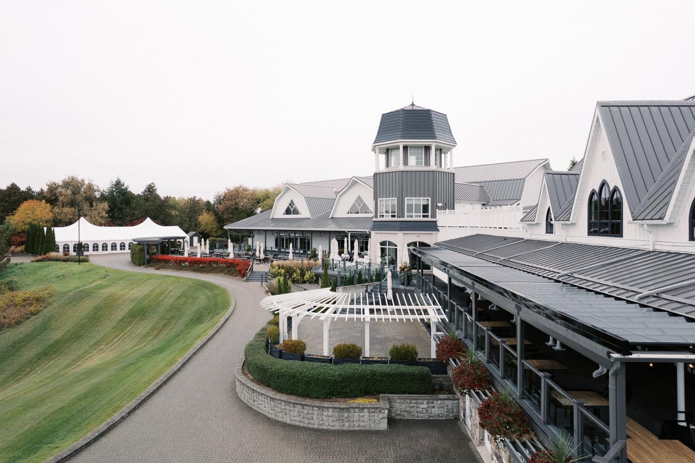 Elegant country club with manicured lawns and modern architecture surrounded by autumn trees.