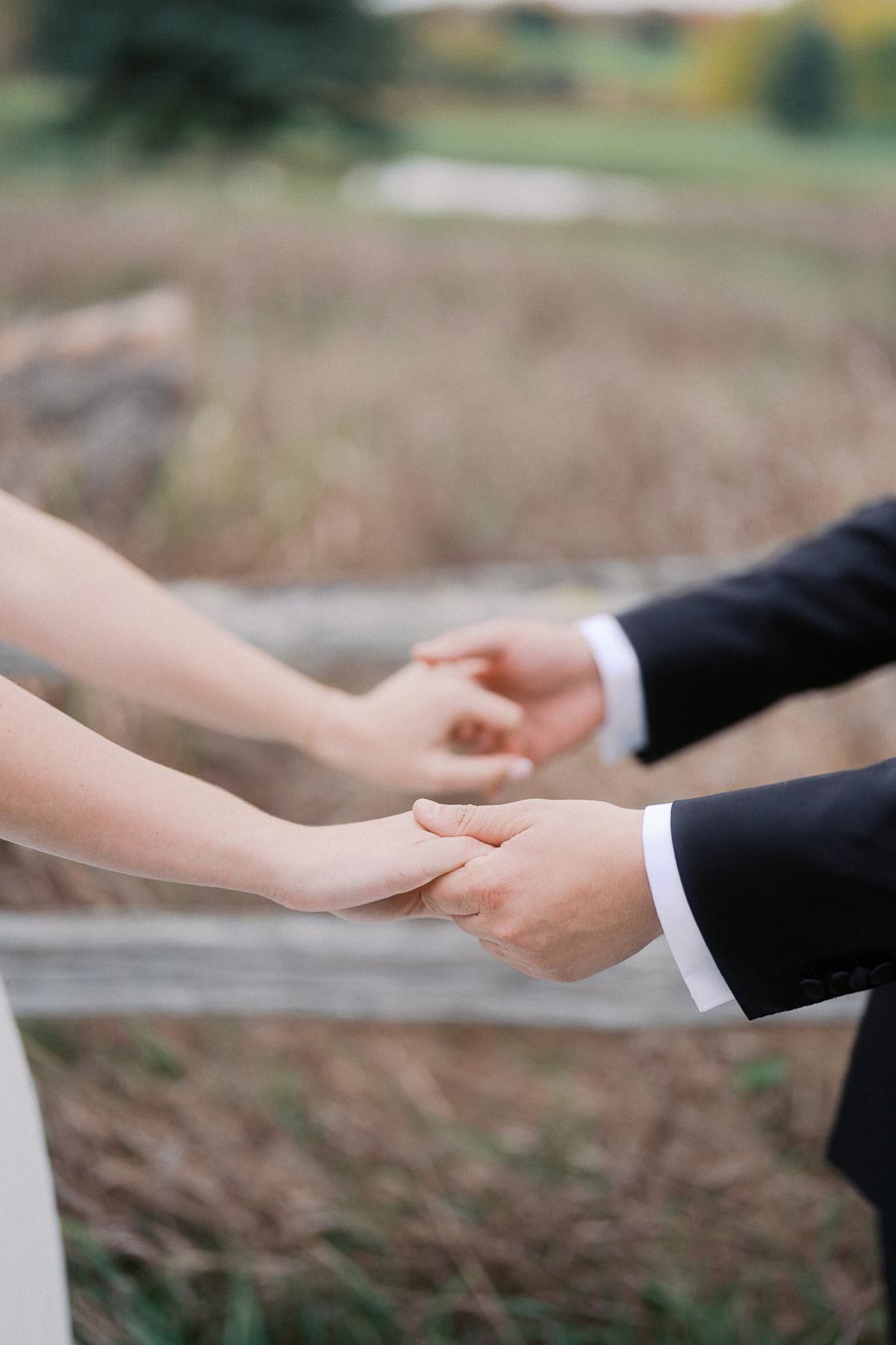 A bride and groom holding hands in an outdoor setting, symbolizing unity and love on their wedding day.