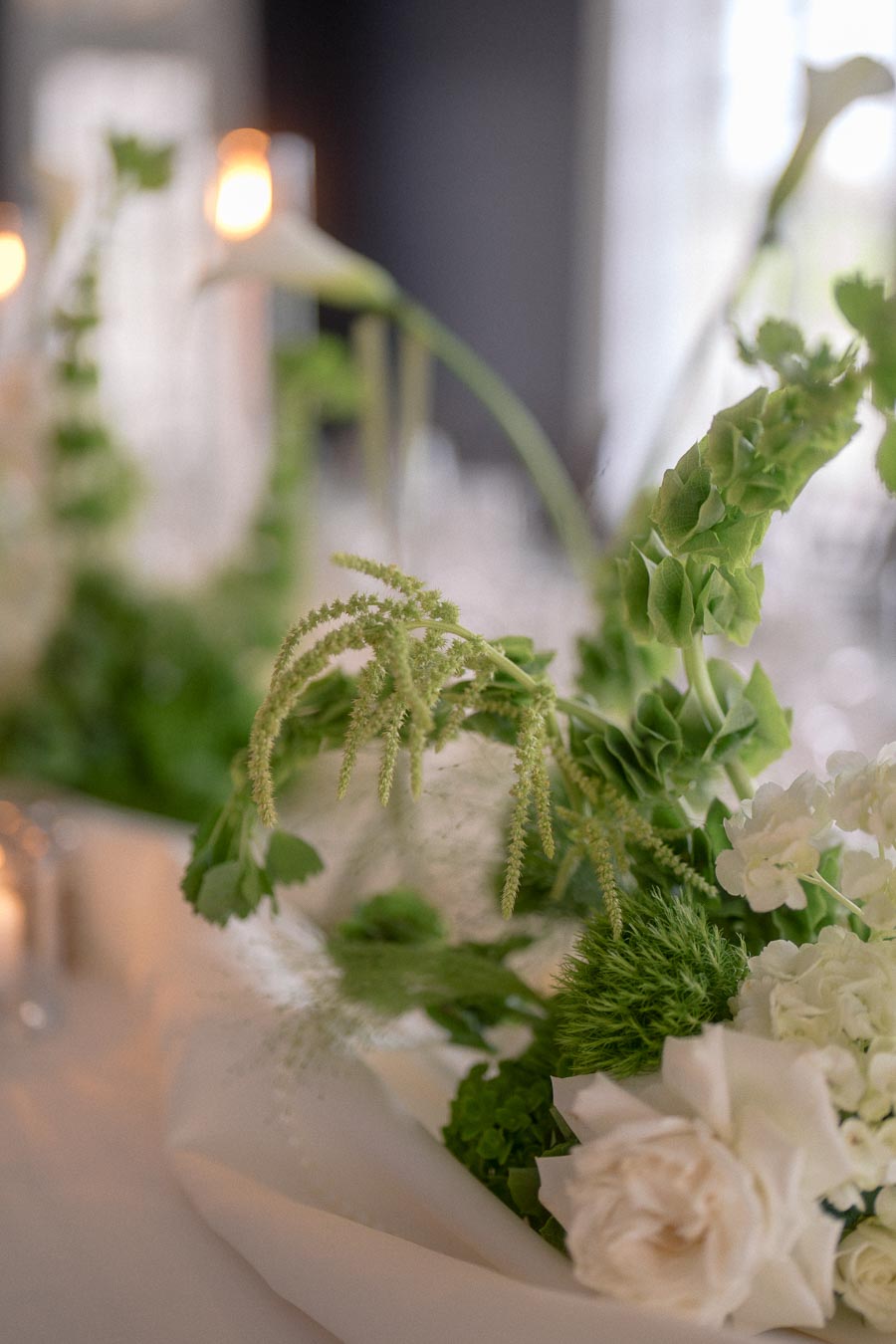 Elegant floral arrangement with white roses, green leaves, and soft lighting, creating a serene and sophisticated atmosphere. Ideal for wedding decor inspiration.