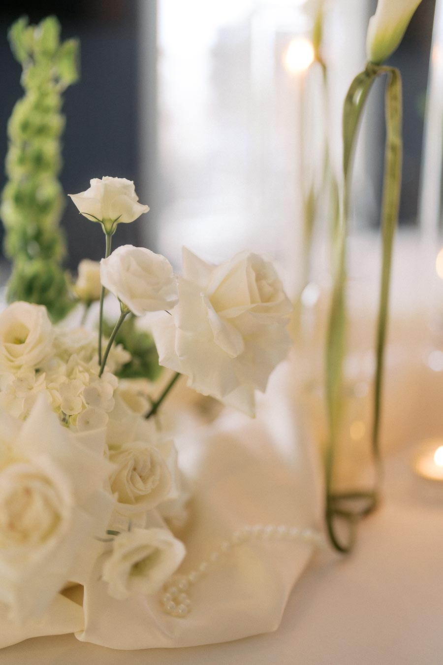 Elegant arrangement of white roses and lisianthus with delicate greenery, set against a softly lit background, emphasizing a romantic and serene ambiance.
