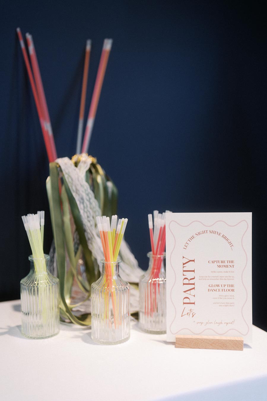 Table setup with colorful glow sticks in glass vases and a festive party sign, perfect for a bright and vibrant celebration atmosphere.