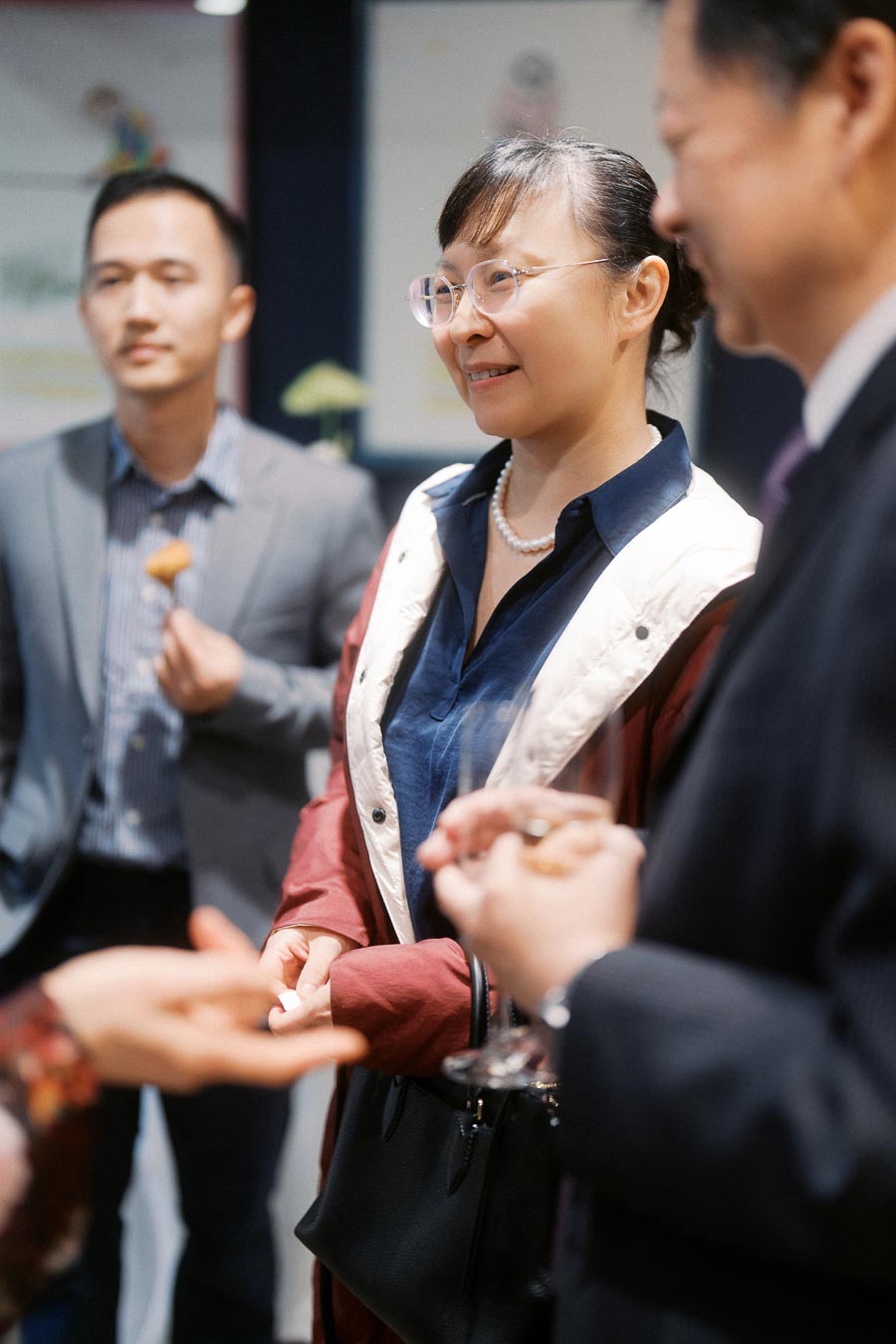 Group of professionals networking at a social event, engaging in conversation and enjoying refreshments.