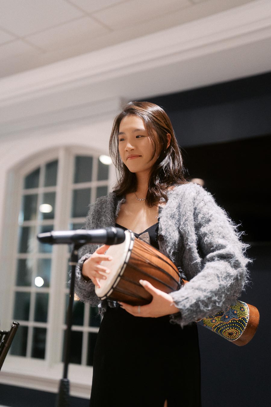 Young woman playing an African drum at a live music event indoors