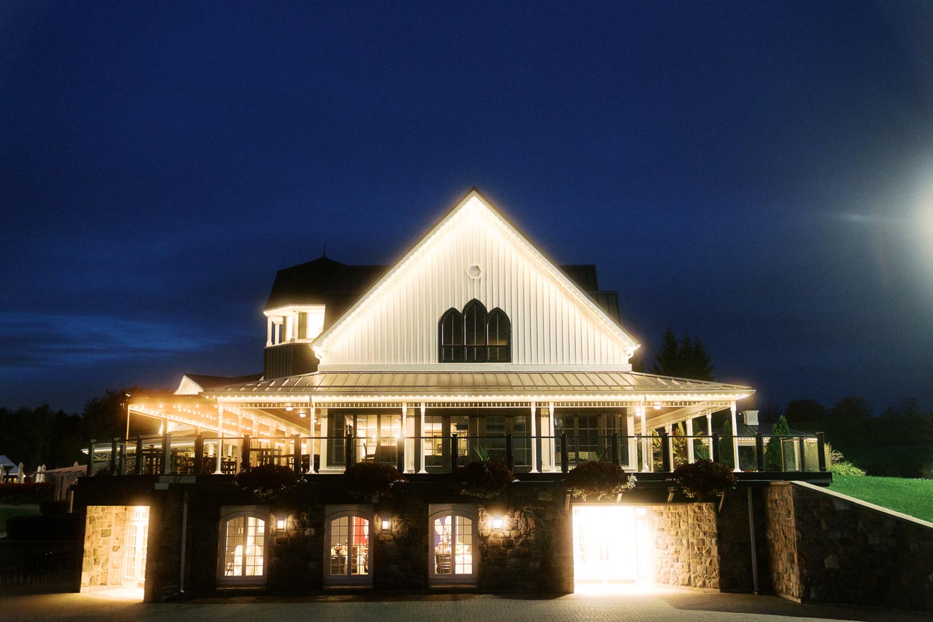 Elegant event venue illuminated at night with fairy lights, showcasing a modern architectural design against a dark sky. Ideal for special occasions and celebrations.