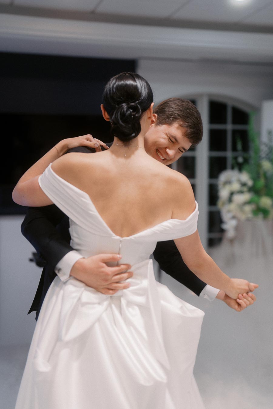 A bride and groom happily dancing during their wedding reception, showcasing a romantic and joyful moment in a beautifully decorated venue.