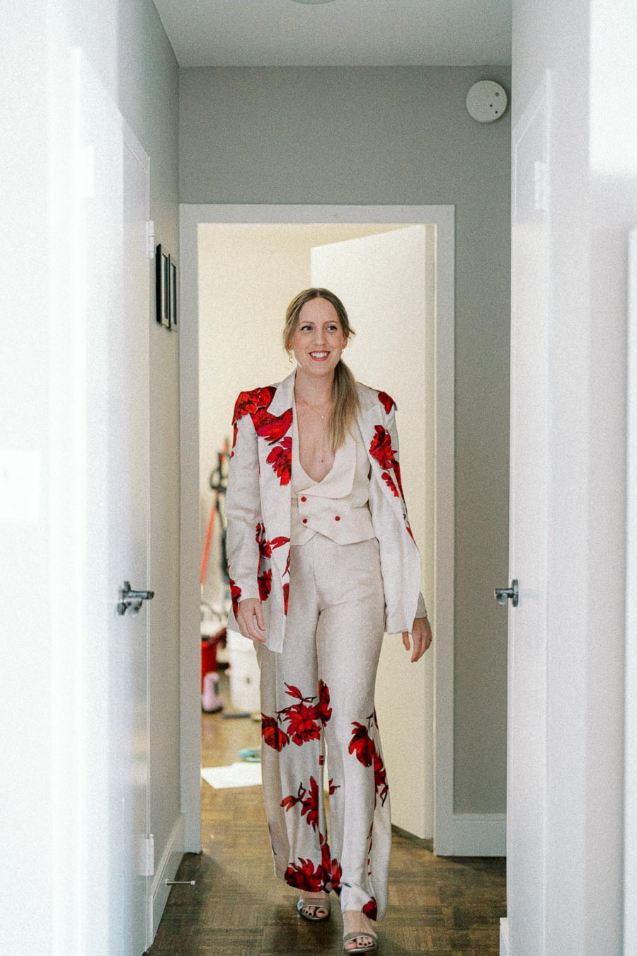 Woman wearing a stylish floral suit walks through a bright hallway, combining elegance with a modern fashion statement.