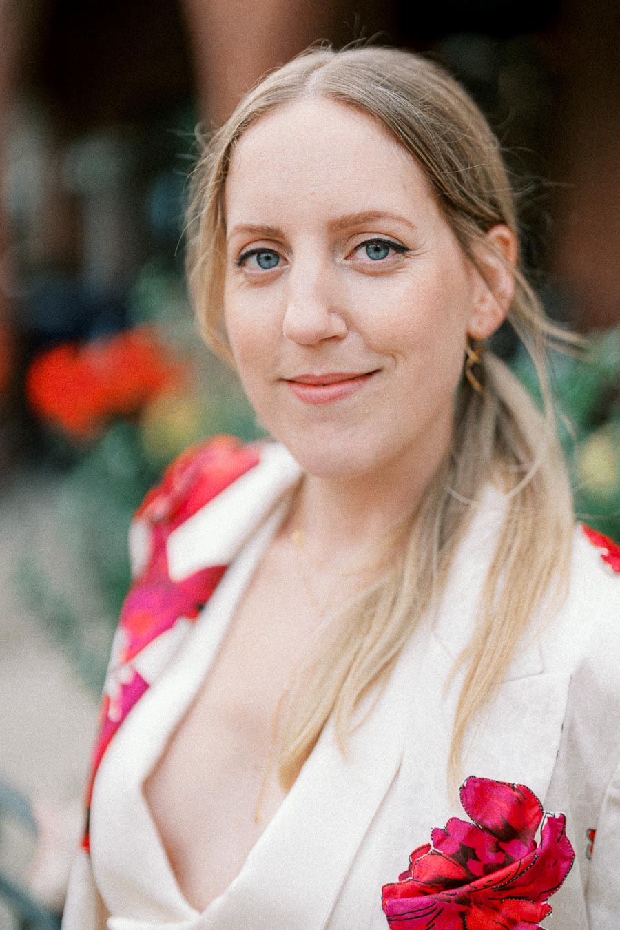 Woman in a floral-patterned blazer in a garden setting, smiling at the camera