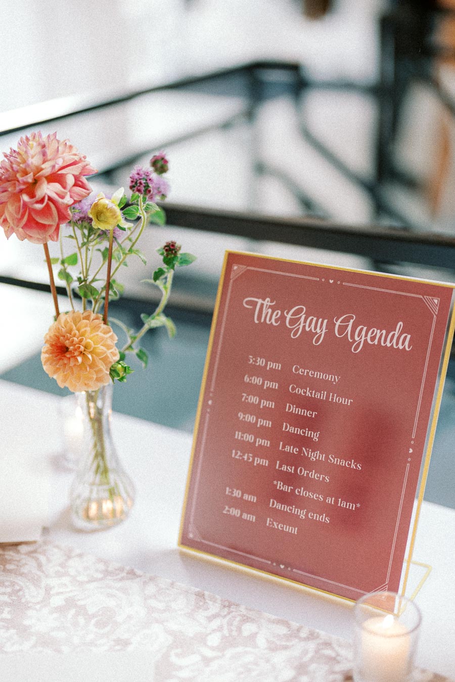 A wedding schedule card with a floral arrangement, detailing event times including ceremony, cocktail hour, dinner, dancing, and late-night snacks.