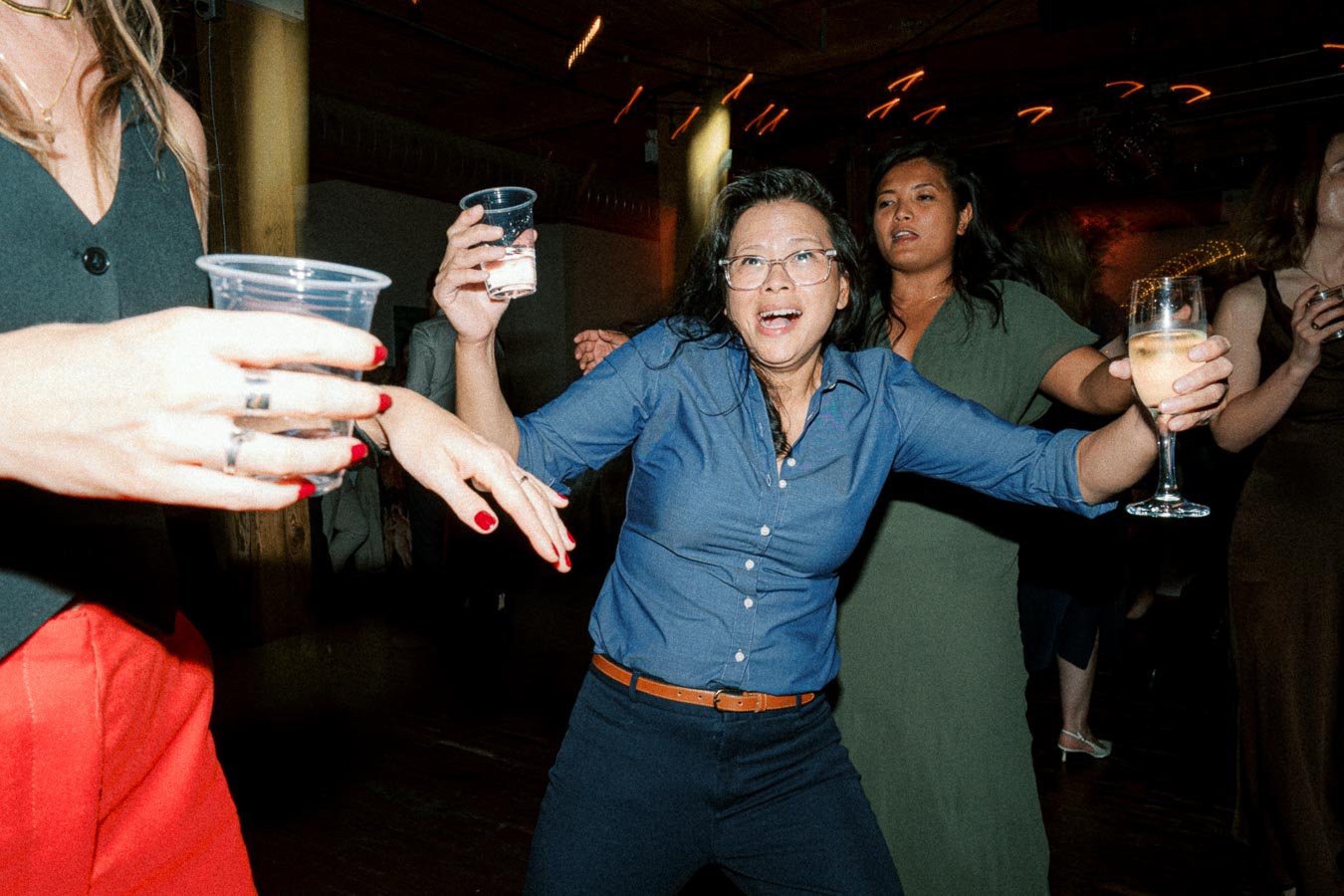 A group of people having fun and dancing at a lively party, holding drinks and enjoying the festive atmosphere.