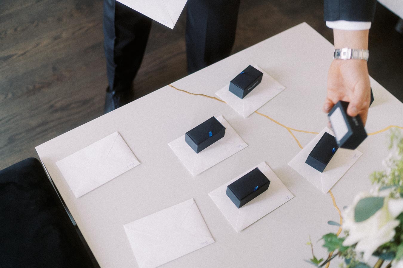 Business professional organizing black gift boxes on a marble table with envelopes, showcasing corporate event preparation.